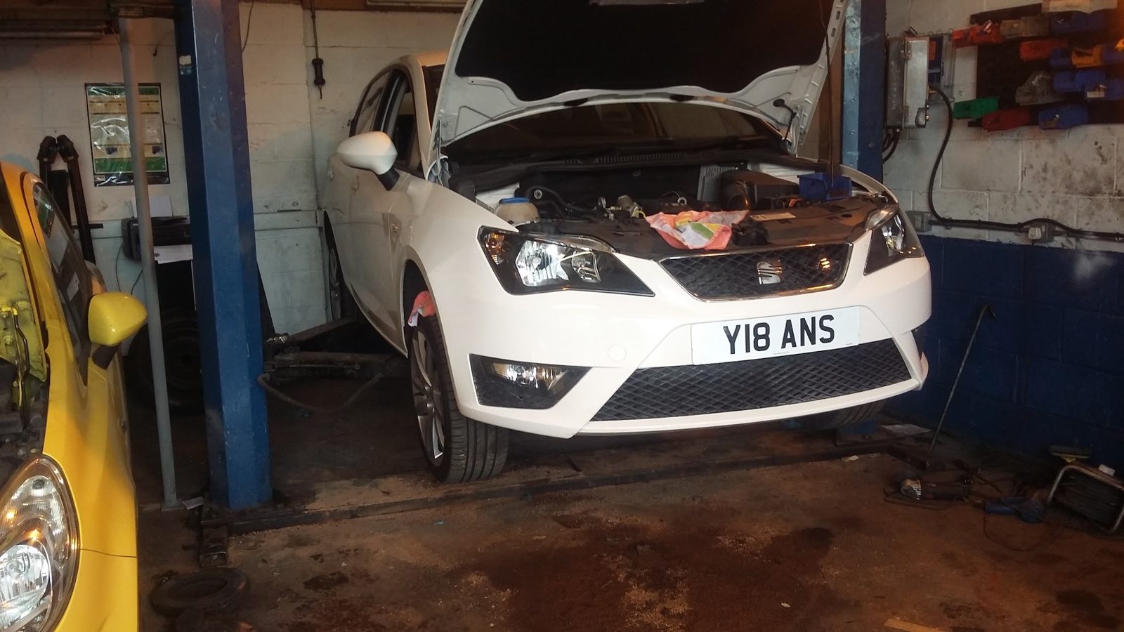 A white SEAT on the lift with its bonnet open