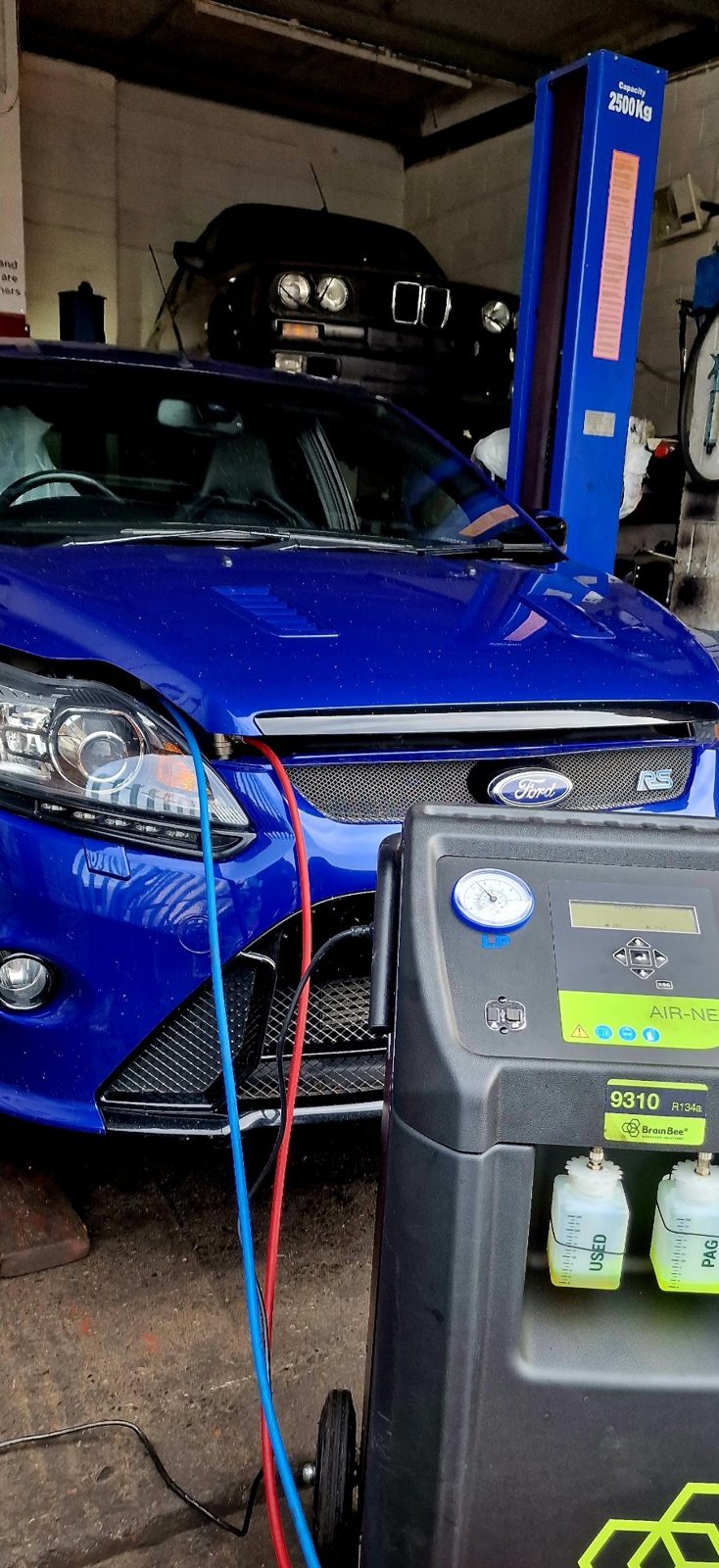 A blue Ford Focus in the workshop, connected to a service machine