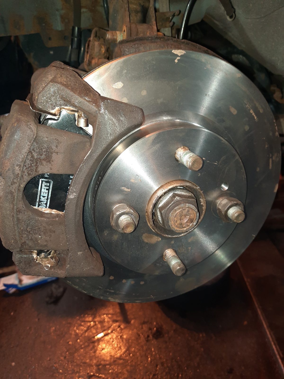 A brake disc and caliper fitted to a car in the workshop